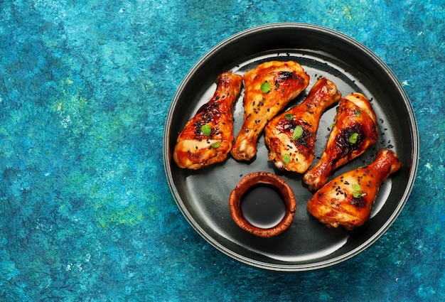 Cuisses de poulet grillées épicées avec sauce soja, sur un plateau. Vue de dessus et espace pour le texte