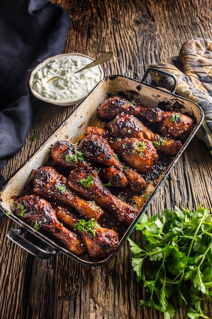 Cuisses de poulet grillées rôties et barbecue dans une poêle avec des herbes et une décoration de sauce tzaziki.