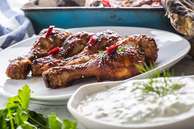 Cuisses de poulet grillées rôties et barbecue sur plaque blanche avec décoration aux herbes.