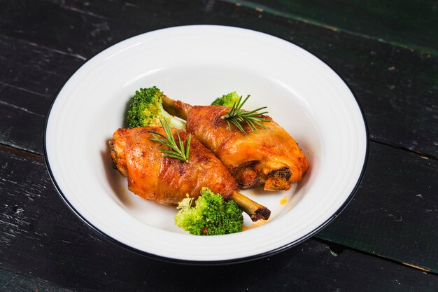 Cuisses de poulet avec des légumes sur une table en bois.