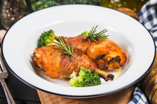 Cuisses de poulet avec des légumes sur une table en bois.