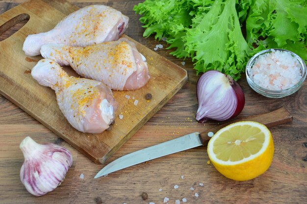 cuisses de poulet sur la planche à découper avec des légumes frais sur le fond en bois