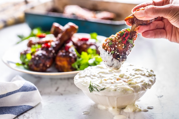 Cuisses de poulet rôties à la main de la femme et sauce tzatziki ou vinaigrette.