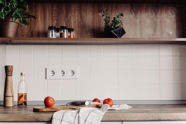 Cuisson des aliments dans une cuisine moderne avec des meubles de couleur grise et un dessus de table en bois Couteau sur une planche à découper en bois avec des légumes, du poivre, de l'huile d'épices Nourriture maison Cuisine élégante