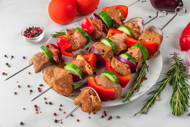 Cuisson barbecue kebab ou shashlik Viande de porc crue avec légumes poivre et oignon sur des brochettes