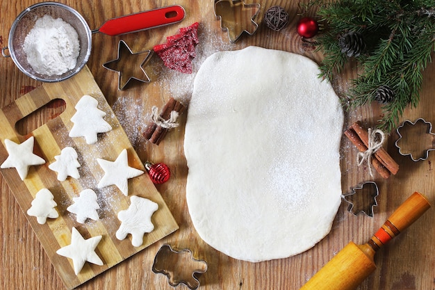 Cuisson des biscuits au beurre de différentes formes sur une table en bois avec des accessoires de Noël