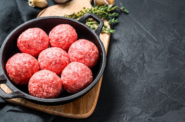 Cuisson des boulettes de viande de porc haché dans une poêle. Fond noir. Vue de dessus. Espace copie