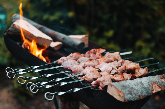 Photo cuisson des brochettes sur le gril sur une brochette en métal. viande. grillades sur braises et flammes, pique-nique, rue