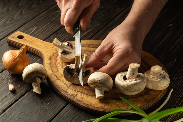 Cuisson des champignons Agaricus par les mains du chef en cuisine Grande cuisine