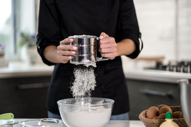 Cuisson dans la cuisine en tamisant la farine dans un bol transparent