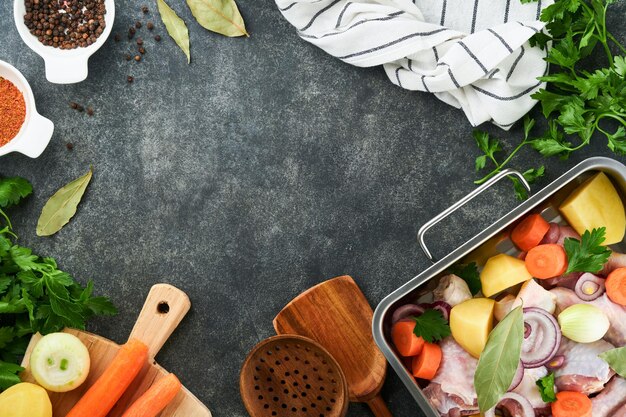 Cuisson du bouillon de poulet ou du rôti dans une casserole ou une marmite avec des légumes pommes de terre carottes et herbes sur le paysage de plan de travail en béton gris de la cuisine d'en haut Cuisson préparation du bouillon de poulet Maquette