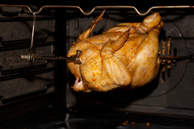 Cuisson du poulet au four ou à la rôtissoire sur un tournebroche. Cuisine à la maison.