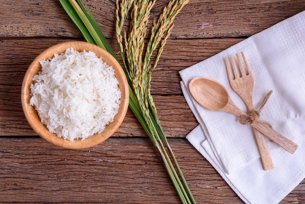 Cuisson du riz blanc (riz thaï Jasmin) dans un bol en bois avec du riz non moulu sur vieux bac en bois