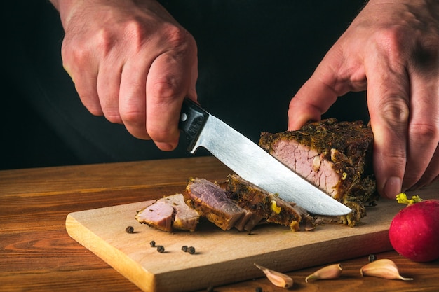 Cuisson du steak de boeuf juteux par les mains du chef sur fond noir foncé avec espace de copie pour le menu texte ou la recette.