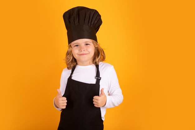 Cuisson des enfants Chef enfant garçon sous forme de cuisinier Enfant garçon avec tablier et toque préparant un repas sain sur fond isolé de studio Processus de cuisson