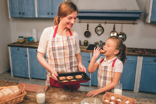 Cuisson des gâteaux faits maison. Une famille aimante et heureuse prépare une boulangerie ensemble. Mère et enfant fille fille préparent des biscuits et s'amusent dans la cuisine. Goûte des biscuits frais