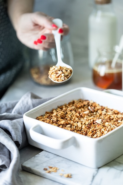 Photo cuisson granola maison. femme remplissant le pot mason avec granola fait maison.