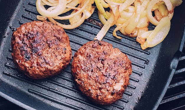 La cuisson de l'hamburger de boeuf haché sur une poêle à frire en fonte à l'extérieur de la viande rouge sur une poêle à griller des aliments dans le jardin La campagne anglaise vivant