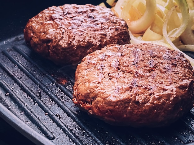 La cuisson de l'hamburger de boeuf haché sur une poêle à frire en fonte à l'extérieur de la viande rouge sur une poêle à griller des aliments dans le jardin La campagne anglaise vivant