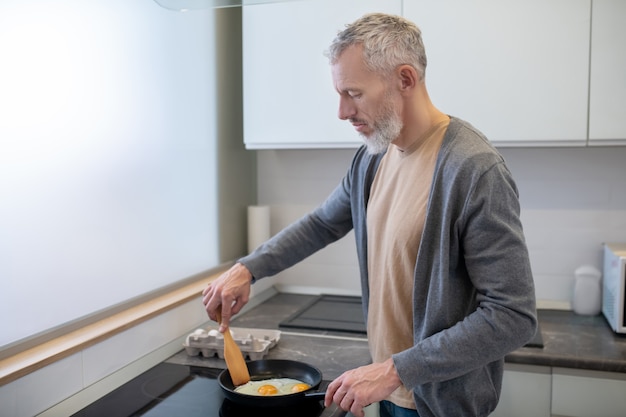 Cuisson. Un homme bardé d'âge mûr cuisine dans la cuisine