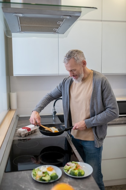 Cuisson. Un homme bardé d'âge mûr cuisine dans la cuisine