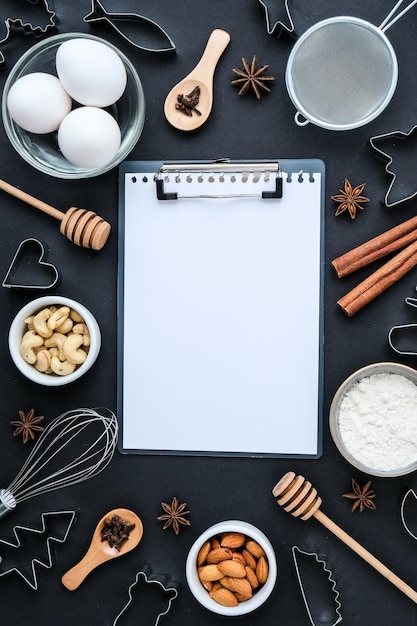 Photo cuisson des ingrédients de cuisine sur fond noir. vue de dessus. espace de copie de presse-papiers vide. pâtisserie maison : biscuits, pain, gâteau. bâtons de cannelle, noix épices oeufs farine