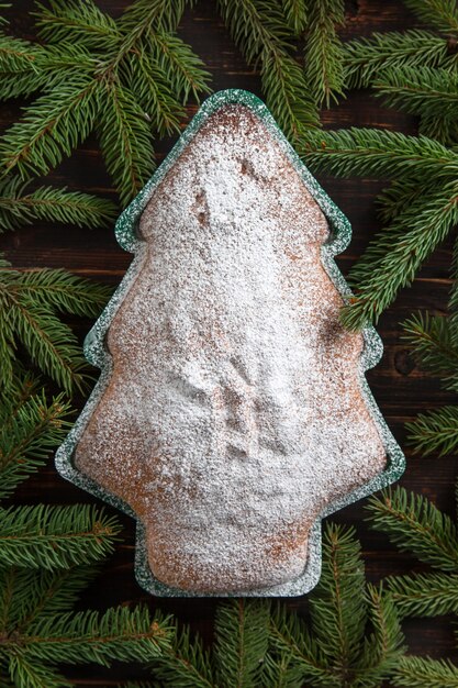 Cuisson maison, biscuits en forme de sapin de Noël, branches de sapin et décorations sur une table en bois. Vue de dessus, mise à plat.