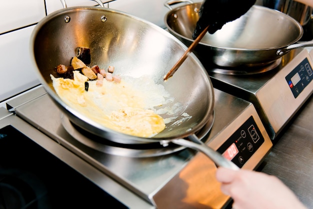 Cuisson des œufs brouillés dans une casserole en métal dans un foyer sélectif de café