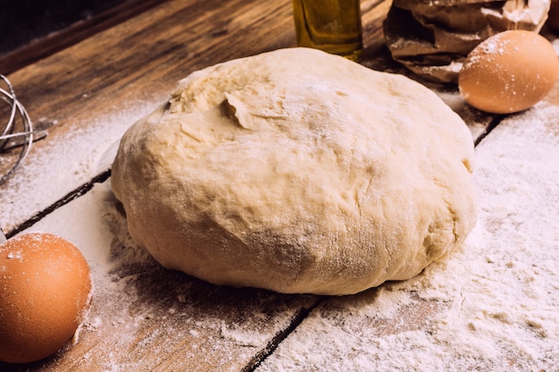 La cuisson de la pâte à pizza dans la cuisine à domicile. Pâte maison pour pain, pizza, pâtisseries et petits pains. Ingrédients de la pâte sur un fond rustique en bois