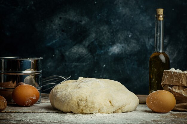 La cuisson de la pâte à pizza dans la cuisine à domicile. Pâte maison pour pain, pizza, pâtisseries et petits pains. Ingrédients de la pâte sur un fond rustique en bois