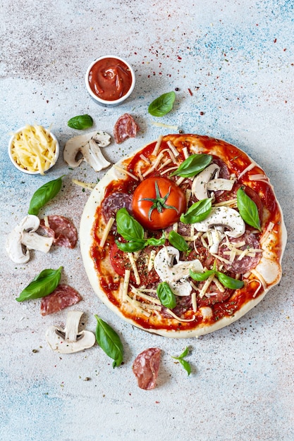 La cuisson de la pizza italienne avec sauce tomate tomates fraîches fromage champignons tranches de salami et basilic