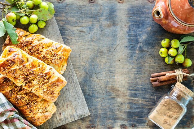 Cuisson à la pomme, pommes fraîchement cuites au four et brioches à la cannelle faites de pâte feuilletée sur une table en bois blanc. Vue de dessus, style rustique, espace copie.