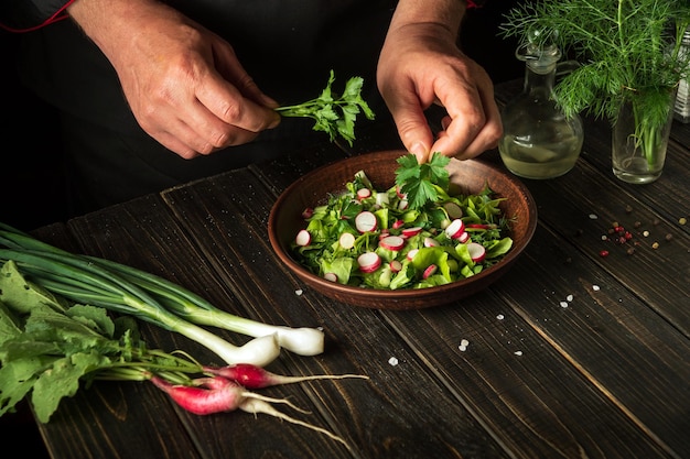 Cuisson d'une salade de légumes frais par les mains d'un chef dans la cuisine Cuisine végétarienne