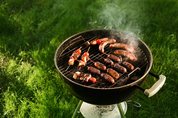 Cuisson de savoureuses saucisses et légumes sur la grille du barbecue à l'extérieur