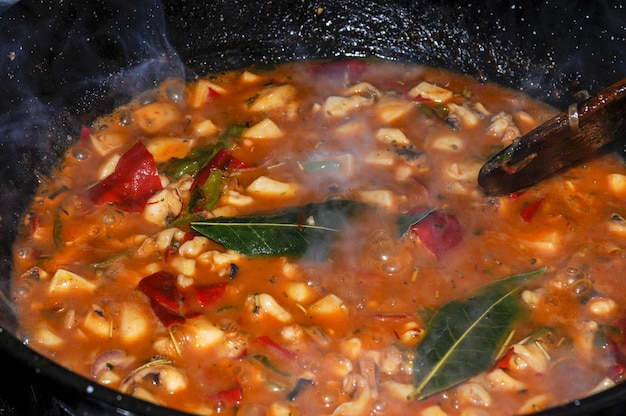 Cuisson des seiches en sauce américaine sur la cuisinière d'une cuisine