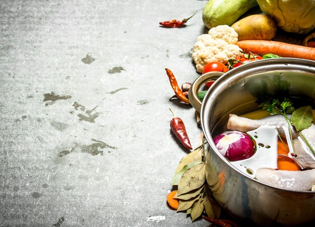 Cuisson de la soupe au poulet avec des légumes dans une grande casserole. Sur la table en pierre.