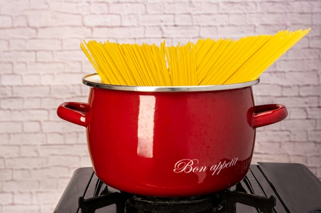 Cuisson des spaghettis dans une casserole sur une cuisinière à gaz Dîner italien fait maison Poêle rouge avec des spaghettis