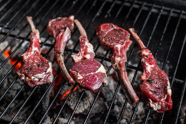 Cuisson des steaks de côtelettes d'agneau cru au barbecue, barbecue extérieur avec feu. Vue de dessus.