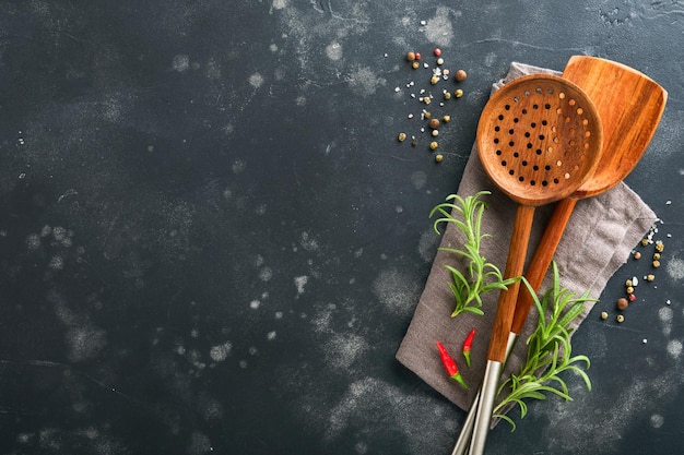 Cuisson des ustensiles en bois feuilles de basilic et épices sur fond en bois ancien Fond de nourriture abstraite Vue de dessus de table de cuisine rustique sombre avec cadre de cuillère de cuisine en bois Bannière pour votre conception