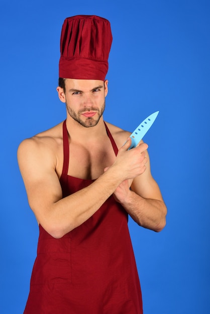 Cuisson des ustensiles de cuisine et des personnes concept homme cuisinier en tablier et chapeau détient un couteau de chef mâle confiant