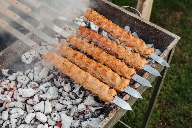 Cuisson de la viande de brochette avec des brochettes sur le gril.