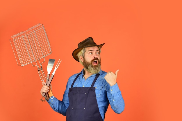 Photo cuisson de la viande saison printanière fermier barbu portant un chapeau et un tablier pour le barbecue rôtir de la viande steak et barbecue barbecue grillades pique-nique et barbecue pique-nique américain tradition familiale