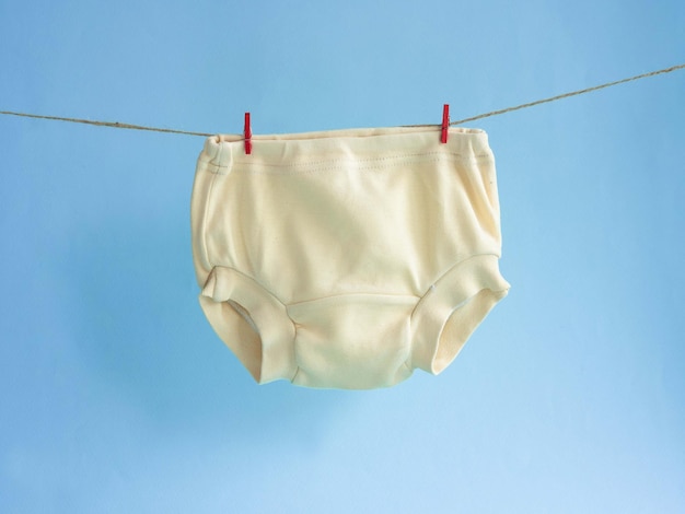 Culotte jaune pour filles accrochée à une corde attachée avec une pince à linge sur fond bleu sous-vêtements en coton tricoté pour enfants