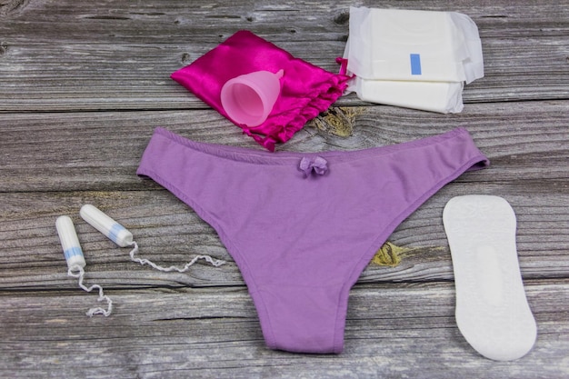 Culottes pour femmes avec coupes menstruelles serviettes hygiéniques et tampons sur fond de bois Concept de jours critiques menstruation hygiène féminine