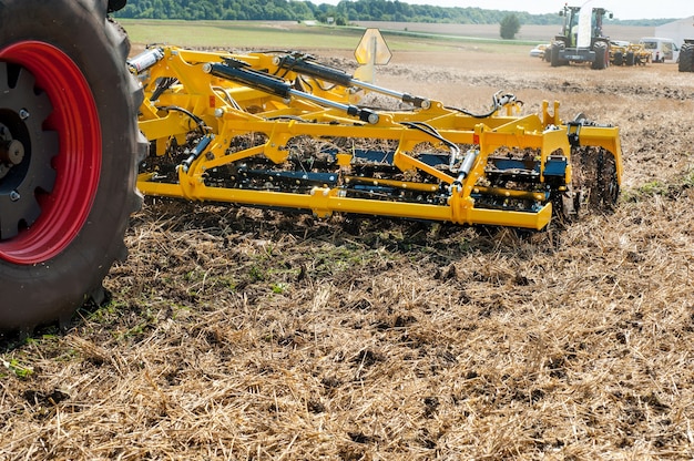 Cultivateur au travail, gros plan d'une herse à disques sur un fond de champ