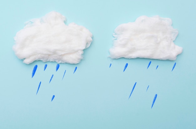 Cumulus en coton avec des gouttes de pluie sur la surface bleue, mise en page pour des idées, espace pour le texte