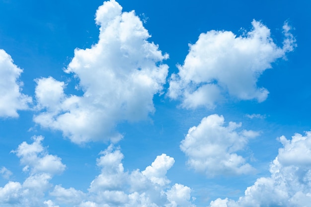 Des cumulus moelleux dérivent contre un ciel bleu clair jetant des ombres douces sur la terre