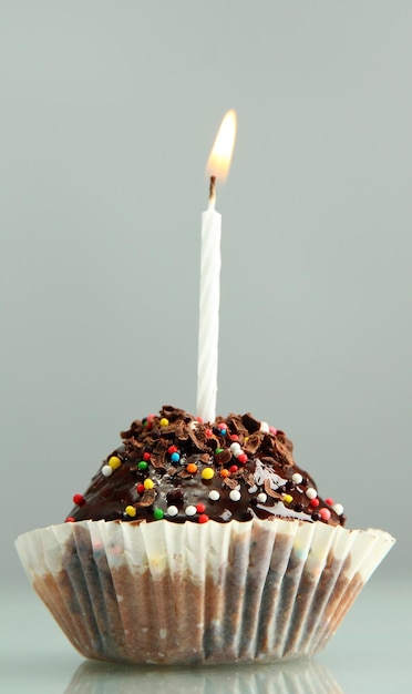 Cupcake d'anniversaire savoureux avec bougie sur fond gris