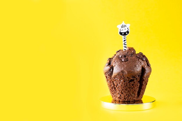 Cupcake au chocolat avec une bougie sur fond jaune Gâteau Bonbons au chocolat Boulangerie Anniversaire