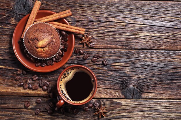 Cupcake au chocolat et tasse de café chaud sur fond de bois foncé, vue de dessus